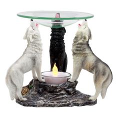 two white wolf figurines sitting on top of a table with a lit candle