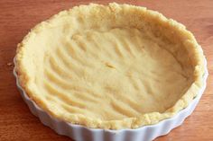 a pie crust in a white dish on a wooden table