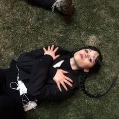 a woman laying on the ground with her hands in her pockets and headphones around her neck