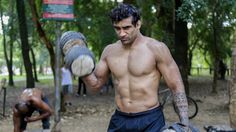 a shirtless man holding two large objects in his hands