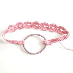 a pink crochet bracelet with a circle on the end and a string attached to it