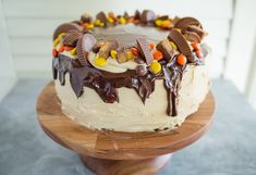 a cake with chocolate frosting and candy on top sitting on a wooden platter