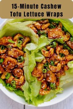 a white bowl filled with lettuce covered in chicken and sesame seed sauce on top of a wooden table