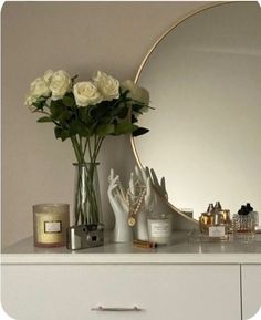 a white dresser topped with lots of vases filled with flowers next to a mirror