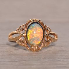 The Aputula: Australian Opal Ring In Yellow Gold. At The Heart Of This Ring Lies An Oval Cabochon Natural Australian Opal, Skillfully Bezel-Set In A North To South Orientation, Showcasing Its Mesmerizing Play Of Color From Every Angle. Encircling The Opal Is An Intricate Filigree Pattern, Which Extends Gracefully Down The Shank, Adding An Extra Layer Of Elegance To The Design. Crafted With Precision In 14 Karat Yellow Gold, This Ring Radiates Warmth And Sophistication. Currently Sized At 5.25, It Can Be Adjusted To Fit Any Finger Size Upon Request For An Additional Charge, Ensuring A Perfect And Comfortable Fit For The Wearer. Australian Opal Ring, Filigree Pattern, Bezel Set Ring, Jewelry Lookbook, Opal Ring, Australian Opal, Jewelry Inspo, Oval Cabochon, Opal Rings