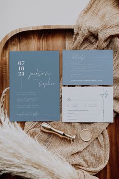 the wedding stationery is laid out on a wooden tray