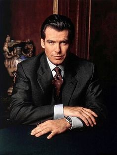 a man in a suit and tie sitting at a table with his hand on the table