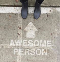 someone standing in front of a sign that says awesome person with an arrow on it