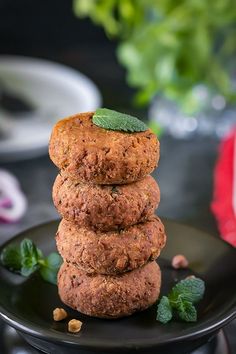 a stack of three cookies sitting on top of a black plate next to green leaves