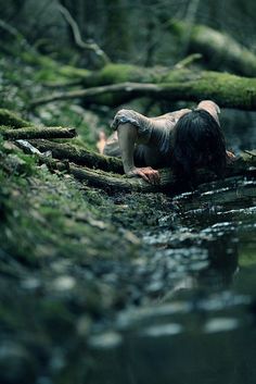 a woman is laying down in the water with moss on her head and body,