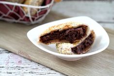 two pieces of chocolate dessert on a white plate next to a basket of pastries