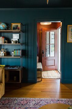 a living room with blue walls and wooden floors, bookshelves on either side of the door