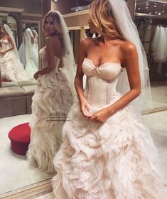 a woman in a wedding dress looking at herself in the mirror with another woman standing behind her