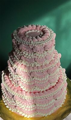 a three tiered cake with pink and white icing on a gold platter