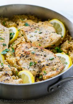 chicken and rice in a pan with lemons, parsley and herbs on top