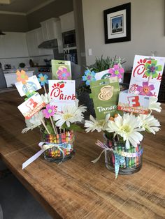 two vases filled with flowers sitting on top of a wooden table next to each other