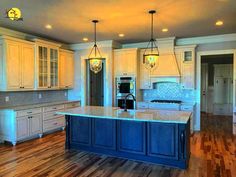 a large kitchen with white cabinets and blue island