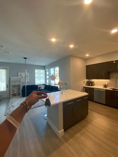 a person is holding up a glass in a large open living room and kitchen area