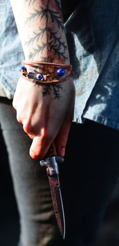 a person holding a knife with evil eyes on it's wrist and wearing bracelets