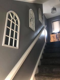 the stairs in this house are painted gray with white trim and arched windows on each side