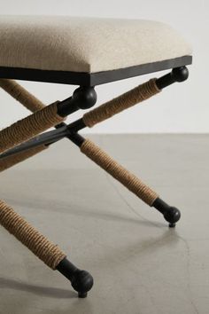 an upholstered chair with rope wrapped around the legs and back rests on a concrete floor