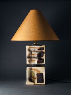 a lamp that is sitting on top of a table next to a light fixture with a brown shade over it