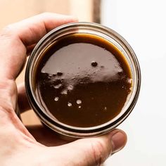 a person holding a glass with some liquid in it and something brown on the inside