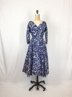 "Vintage 1950s fit n flare dress in white, blue and turquoise Wide V neck Elbow length dolman sleeves with two fabric covered buttons at each opening Multiple bust darts Metal zipper down back and a single hook and eye for closure Fitted waist with self fabric belt Full pleated skirt With a built in crinoline and two front pockets MEASUREMENTS Fits like a Small Shoulders: 16\" Bust: up to 36\" Waist: 26\" Torso: 15\" Hips: Free Sleeve length: 12.5\" Sleeve opening: 4.5\" diameter Length 45\" Bra Vintage Blue A-line Midi Dress, Blue Vintage A-line Midi Dress, 1950s Style Lined Dress With Full Skirt, 1950s Style Dress With Full Skirt And Lining, Retro Blue Tea Length Dress, Retro Blue Tea-length Dress, 1950s Style Lined Dresses For Daywear, Vintage Blue A-line Dress, Blue A-line Vintage Fashion Dress