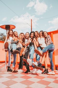 a group of young women sitting on top of a pink and white checkered floor