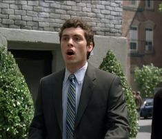 a man in a suit and tie standing on the street with his hands out to someone