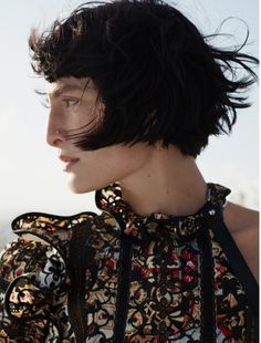 a woman with black hair wearing a patterned top