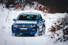 a blue truck driving down a snow covered road