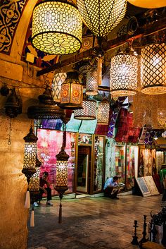 many lamps are hanging from the ceiling in a room that is decorated with intricate designs