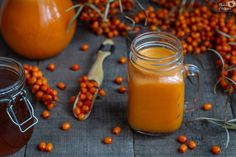 two jars filled with orange juice next to some baby carrots and other fruit on the table