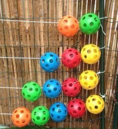 colorful plastic balls are lined up on a fence