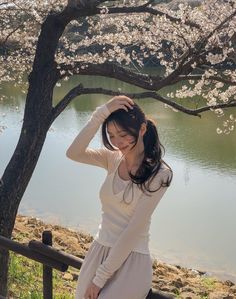 a woman standing next to a tree with flowers on it