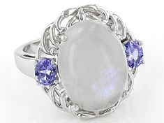 16x12mm Oval Cabochon Rainbow Moonstone With 0.68ctw Oval Tanzanite Rhodium Over Sterling Silver Ring. Measures Approximately 0.78"L x 0.63"W. Not sizeable. White Oval Cabochon Moonstone Ring With Gemstone, White Moonstone Ring With Oval Cabochon, White Oval Cabochon Moonstone Ring, Oval Moonstone Ring In White Gold, White Gemstones With Accents Fine Jewelry, Oval Moonstone Ring With Gemstone Accents, White Oval Jewelry With Gemstone Accents, White Oval Cabochon Gemstones, Oval Silver Moonstone Ring With Accent Stones