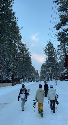 three people walking in the snow with skis on their back and one person carrying two sleds