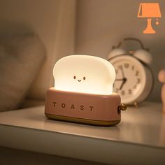 a toast shaped light sitting on top of a table next to an alarm clock and teddy bear