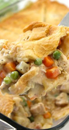 a spoonful of chicken pot pie with peas and carrots on it, in a casserole dish