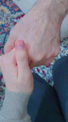 a close up of a person's hand holding another persons wrist on a rug