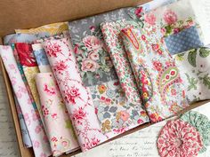 a box filled with lots of different types of fabric next to a piece of paper