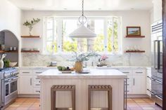 a kitchen with two stools in front of the counter and an island that has plants on it