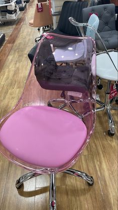 a pink chair sitting on top of a hard wood floor next to chairs in a store