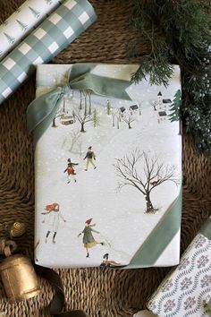 presents wrapped in wrapping paper on top of a wicker mat with christmas tree and snow scene