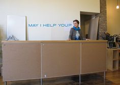 a woman standing behind a reception desk in an office