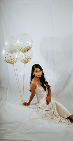 a woman sitting on the floor with balloons in front of her and posing for a photo