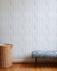 a room with a bench, basket and wallpaper on the wall next to it