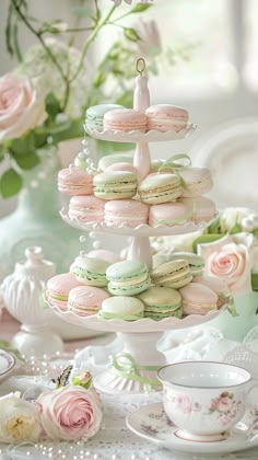 there is a cake stand that has many macaroons on it and flowers in the background