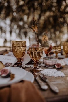 the table is set with gold goblets and plates